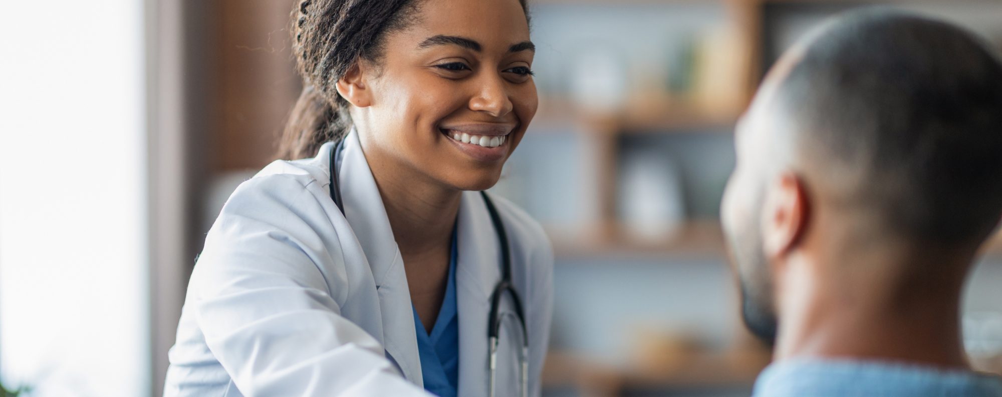 Woman in lab coat smiling while talking to man